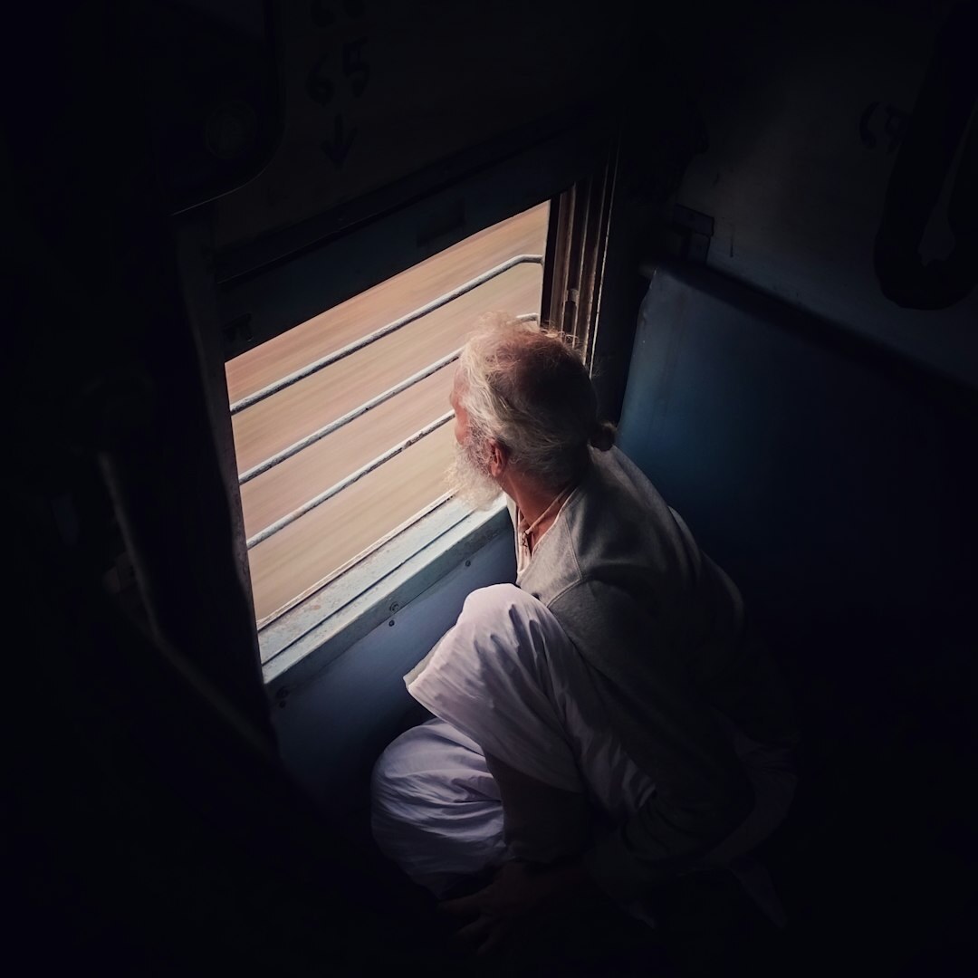 Man sitting quietly by a window reflecting with a notebook on his lap